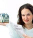 A woman holding a miniature house and a form reading "tax credit" 