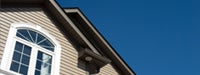 A brown house with white trim and the sky
