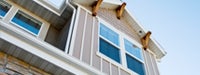 A cream house with white trim, wooden accents and the sky