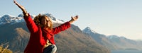Retirement Guide: Female on mountaintop with arms raised in the air, smiling
