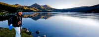Retirement Guide: Senior man standing by clear lake and mountains