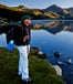 Retirement Guide: Senior man standing by clear lake and mountains