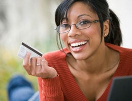 Young woman smiling and holding a credit card