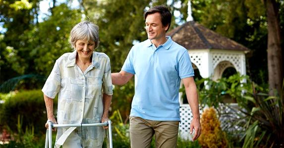 Tax help in caring for aging parents Adult son walking with senior parent in a walker | Morsa Images/Getty Images