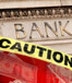 A caution sign with "Bank" and red lights in the background