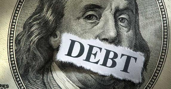 Do I still owe the debt if it's charged off? Benjamin Franklin's mouth covered with the word 'debt' | iStock.com/DNY59