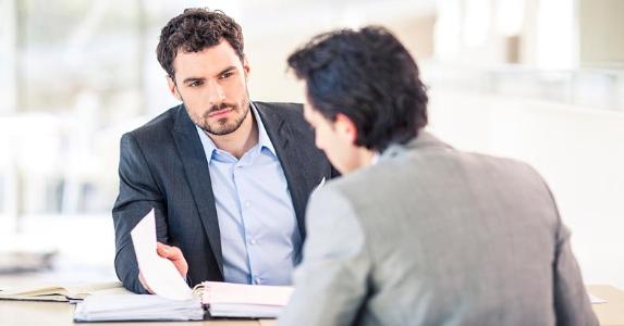Can you expect a pay increase in 2016? Boss and employee sitting at table, reviewing binder | iStock.com
