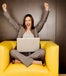Business woman sitting on an armchair with her laptop, cheering