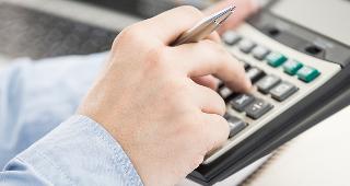 Businessman analyzing investment charts with calculator © Nonwarit/Shutterstock.com