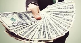 Businessman displaying a spread of hundred dollar bills © Melpomene/Shutterstock.com