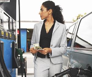 Businesswoman counting money while looking at meter of gas pump © bikeriderlondon/Shutterstock.com