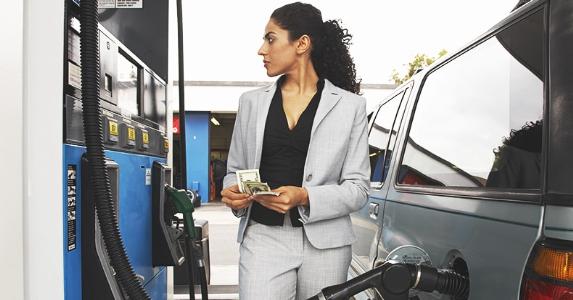 Businesswoman counting money while looking at meter of gas pump © bikeriderlondon/Shutterstock.com