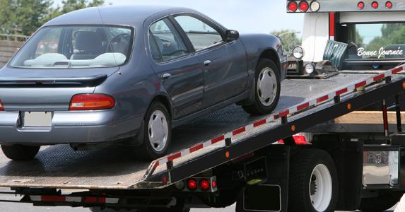 Car being lifted onto tow truck bed