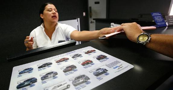 Car rental employee handing packet to customer | Brian Vander Brug/Los Angeles Times/Getty Images