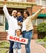Happy family cheering in front of their sold house