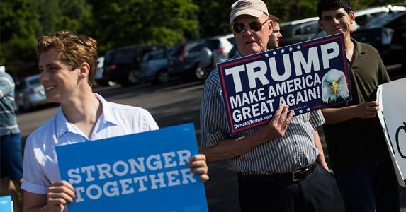 Election is economy's biggest threat, survey say Hillary Clinton and Donald Trump supporters standing side-by-side holding signs | Boston Globe/Getty Images