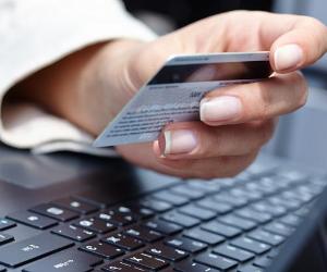 Close-up of woman holding credit card near laptop © Denis Vrublevski/Shutterstock.com