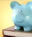 books stacked with a blue piggy bank on top