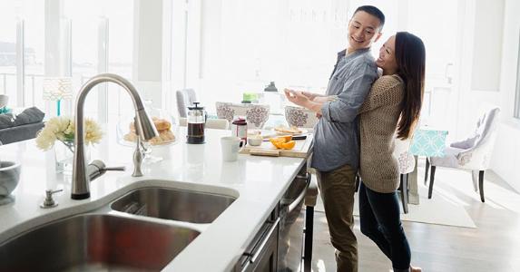 Burning questions your mortgage lender will ask Couple embracing in the kitchen | Hero Images/Getty Images