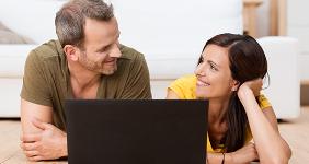 Couple sharing laptop laying on the floor together © racorn/Shutterstock.com