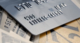 Black credit card on table with money underneath