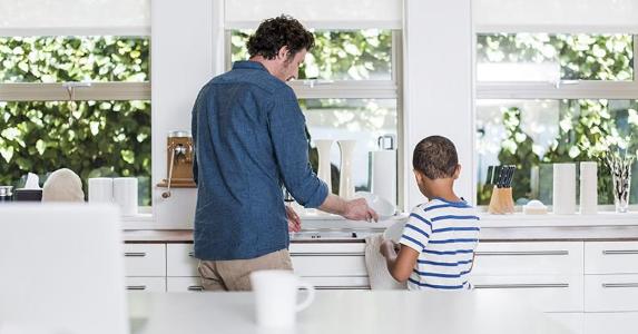 Dad and young son drying dishes in the kitchen | Portra Images/DigitalVision/Getty Images