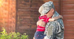 Dad in military clothes hugging young son @ PEPPERSMINT/Shutterstock.com