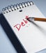 "Debt" written in red being erased off a spiral notepad