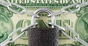 A black lock with 4 silver chains over a dollar bill 