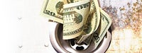 A couple 20 dollar bills going down a dirty drain