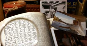 Magnifying glass on words "Retire" in dictionary, surrounded by photos and a candle