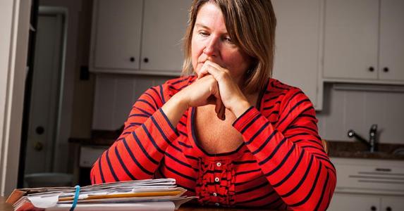Can your wages be seized if you have power of attorney? Dismal woman staring at piles of bills on kitchen table | iStock.com/Fertnig