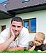 family laying down front of house