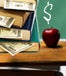A desk, with books, an apple and $ signs on the board