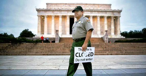 Who loses in a government shutdown? Government employee holding 'This site is CLOSED' sign | Andrew Harrer/Bloomberg/Getty Images