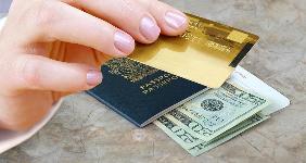 Hand holding credit card with passport and money on desk © NAN728/Shutterstock.com