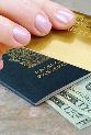 Hand holding credit card with passport and money on desk © NAN728/Shutterstock.com