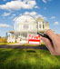 Hand holding magnifying glass in front of house