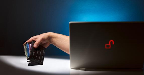 Hand stealing wallet from laptop © GDubbed/Shutterstock.com