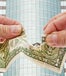 Hands ripping a dollar bill in front of corporate glass building