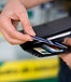 Hands holding a black wallet and pulling out a blue credit card, many others in wallet