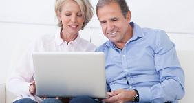 Happy mature couple sitting on couch working on laptop © Andrey_Popov/Shutterstock.com
