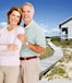 Happy retired couple. Beach front house with wooden walkway.