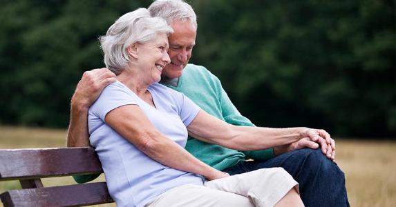 Retirement benefits cut by windfall provision Senior couple sitting on bench in field | I love images/Getty Images