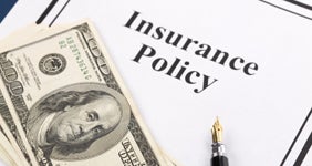 Insurance policy with fountain pen and $100 bills