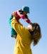 A mother wearing yellow picking up her child