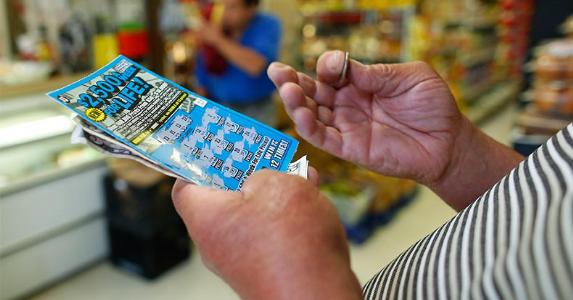Man holding scratch-off lottery ticket | Boston Globe/Getty Images