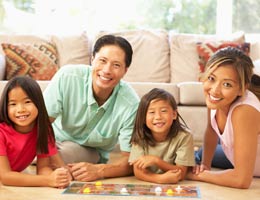 Make at-home vacation worthy Family of four playing a board game