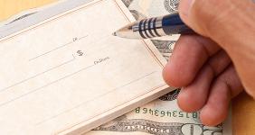 Male hand writing check on money © jcjgphotography/Shutterstock.com