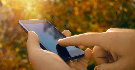 Male hands using smartphone, nature background © PureSolution/Shutterstock.com